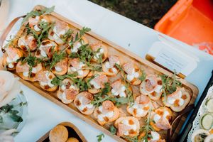 Fresh shrimp skewers garnished with herbs and seasonings lined up on a white serving platter.