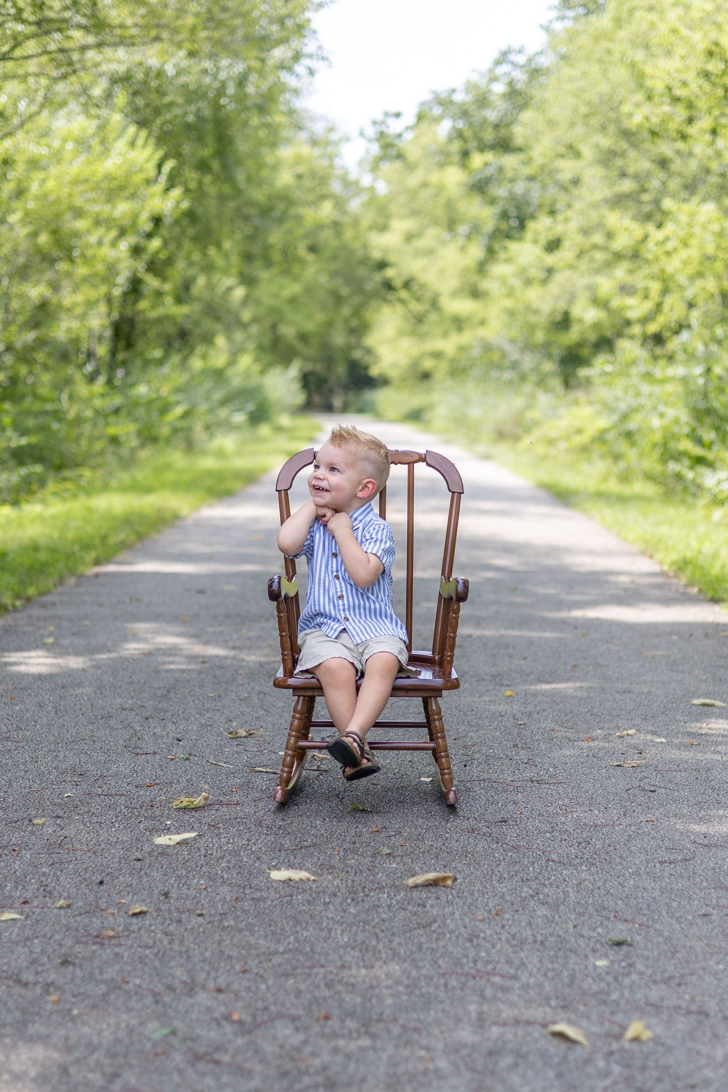 Springfield, IL Photographer captures a boy smiling  with his hands folded while sitting during a milestone session in Central, IL