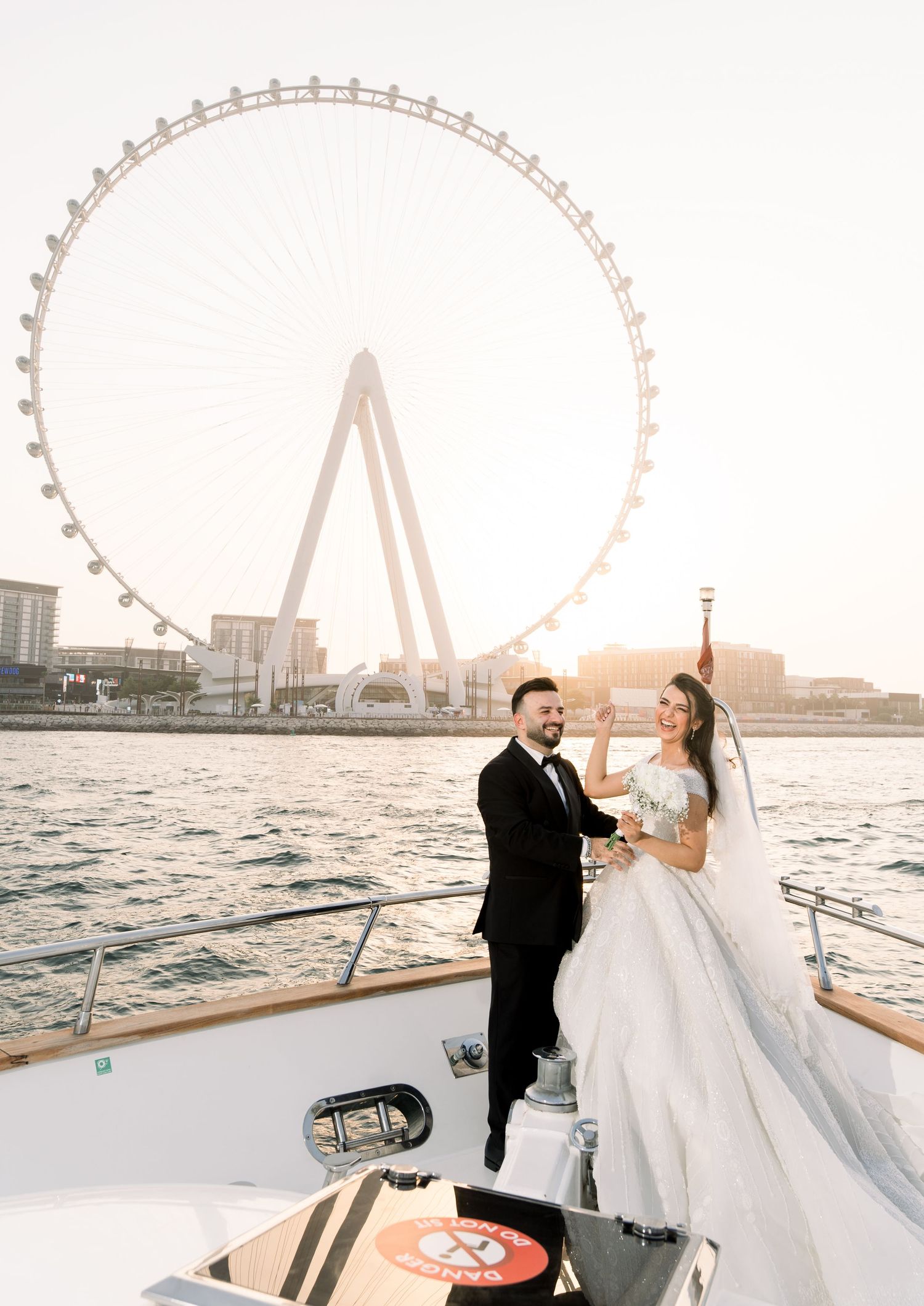 A couple shares a romantic moment on a yacht with the Dubai Eye observation wheel visible in the background.
