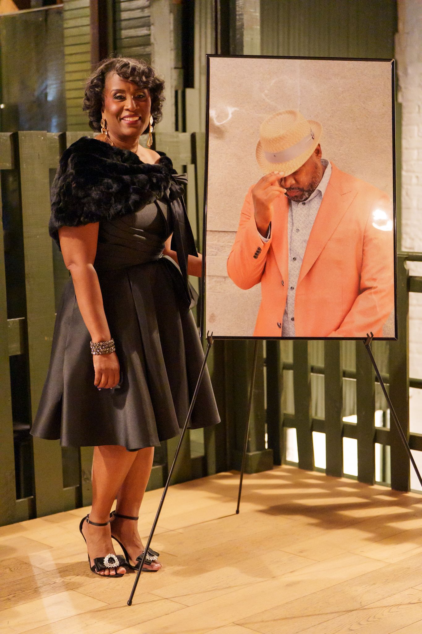 A person in an emerald green velvet dress poses against a decorative green wall backdrop.