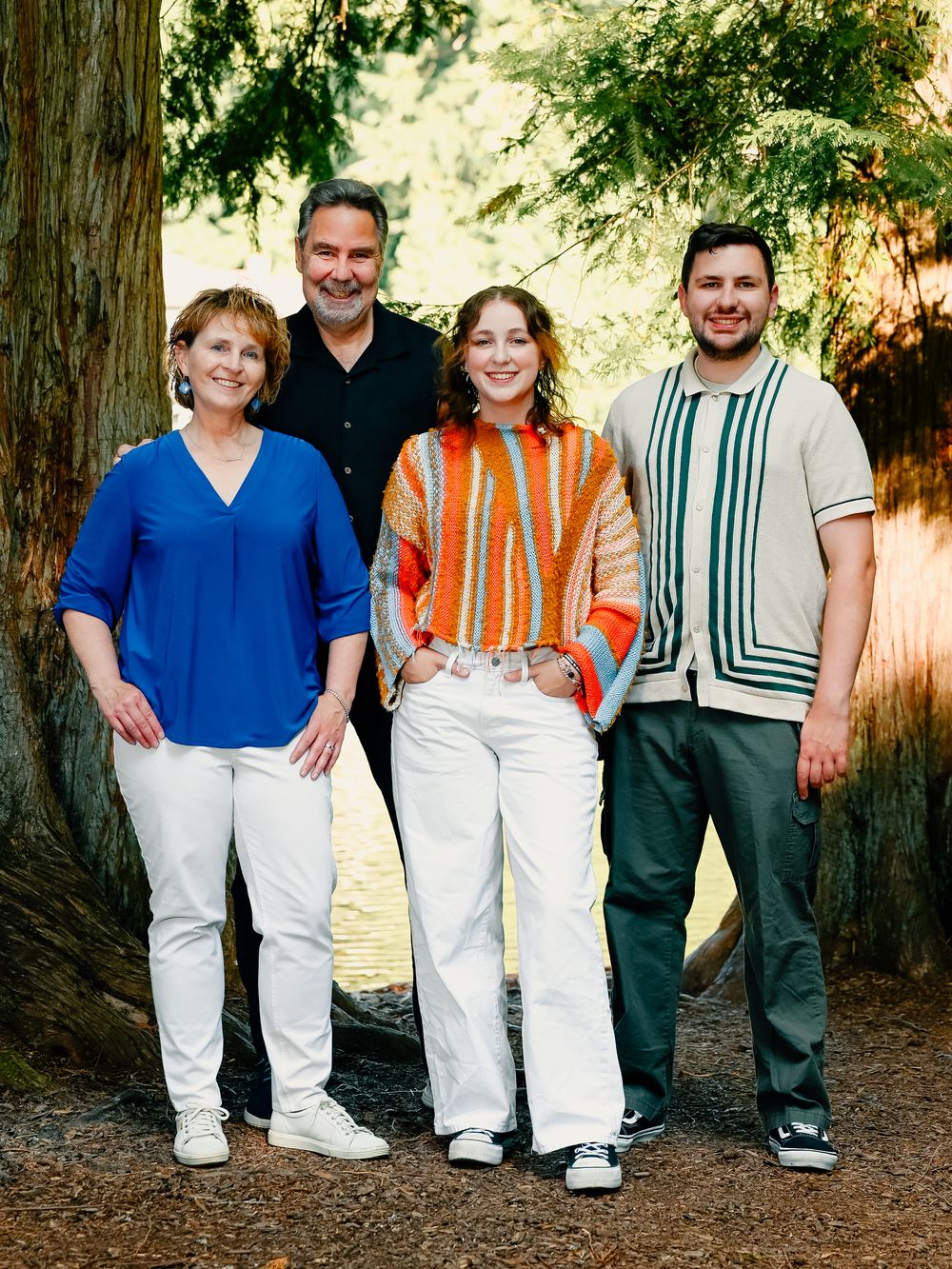 Group photo of people leaning against redwood trees wearing coordinated white and blue outfits.