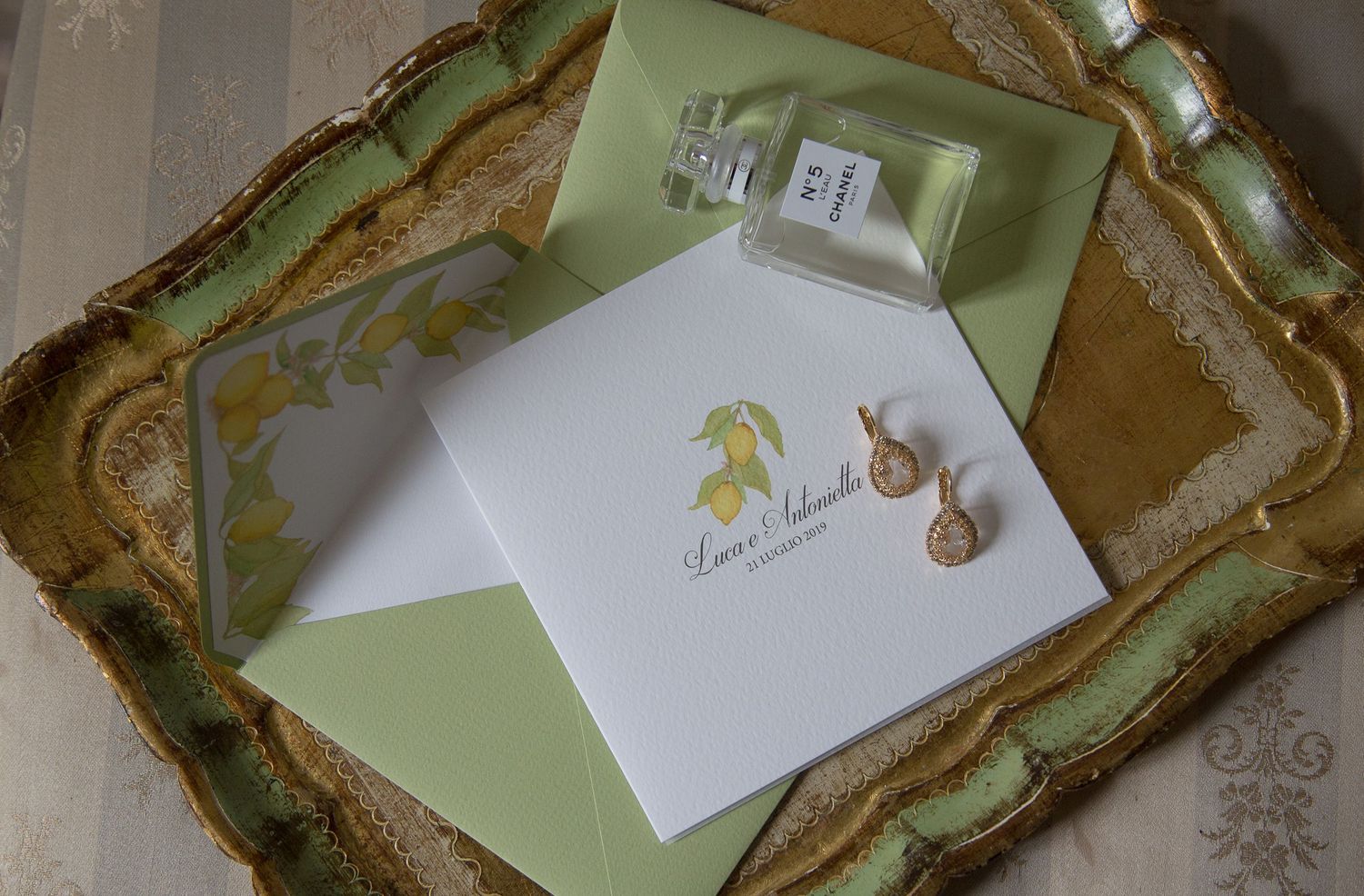 Sage green and gold vintage ornate tray holds elegant white wedding stationery and correspondence items.
