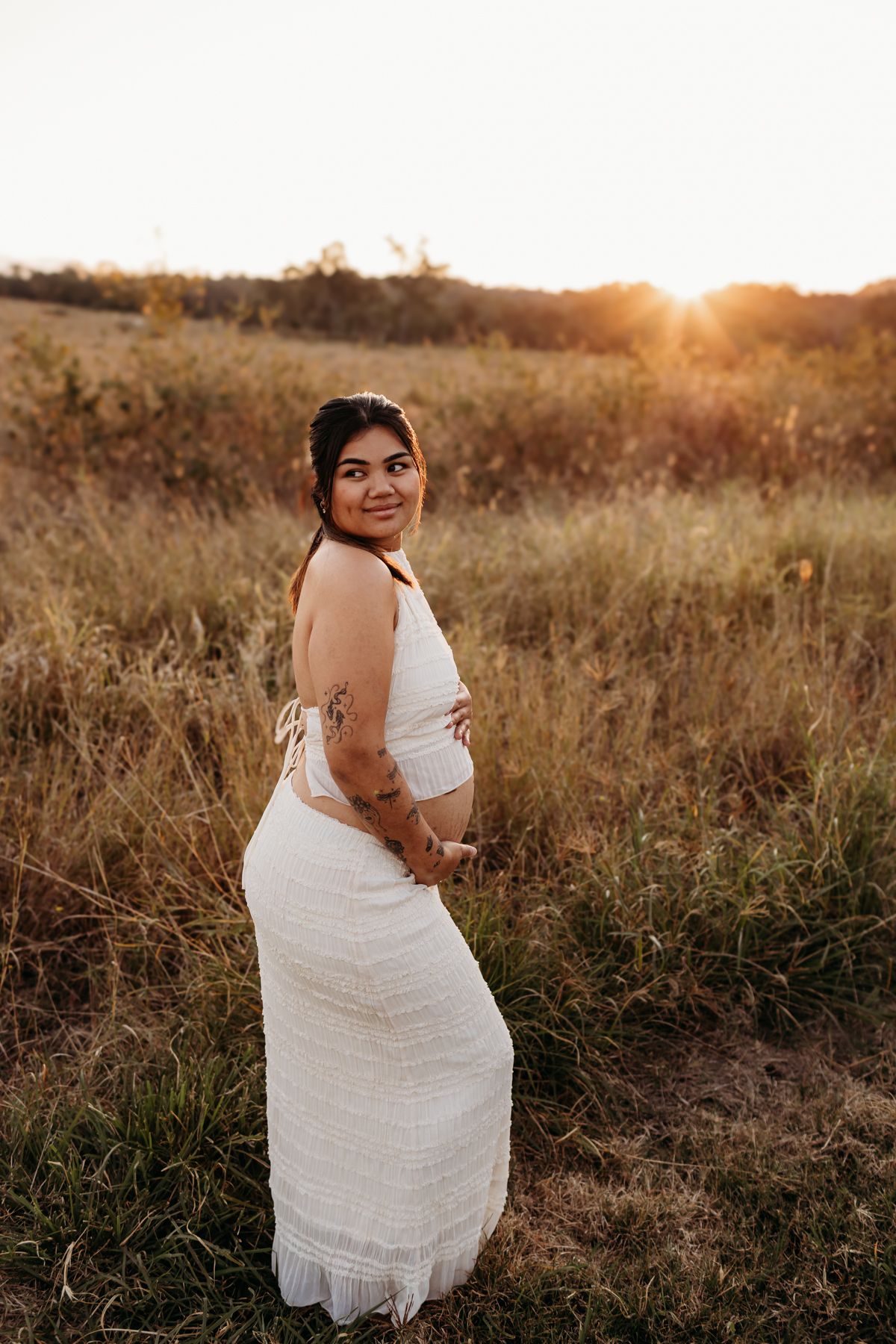 White lace dress photographed in golden field at sunset.