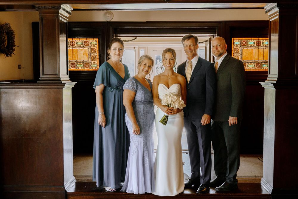 Wedding party members pose for formal portraits in an elegant indoor venue with illuminated decorative panels.