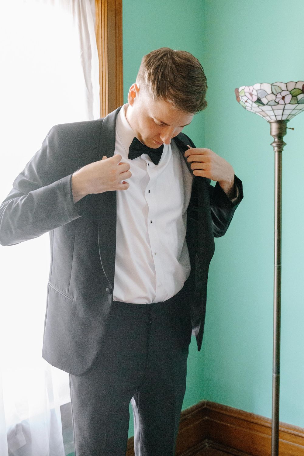 A sequence showing someone in a suit adjusting their shirt collar against a mint green wall.