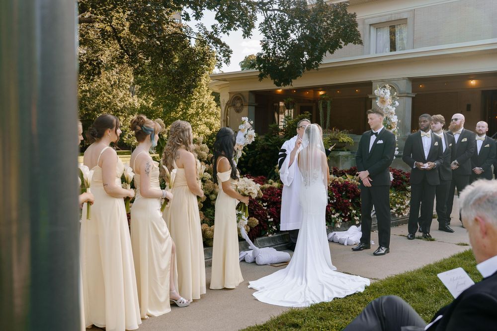 An outdoor wedding ceremony lineup against a white colonial style building with columns.