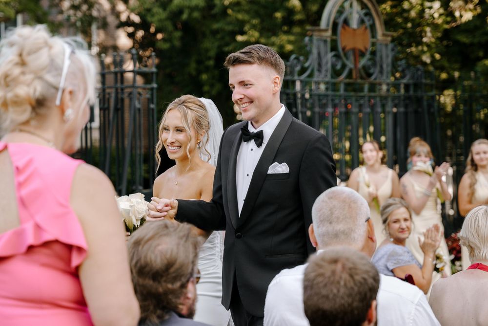 A joyful wedding ceremony takes place outdoors with guests watching the happy couple.