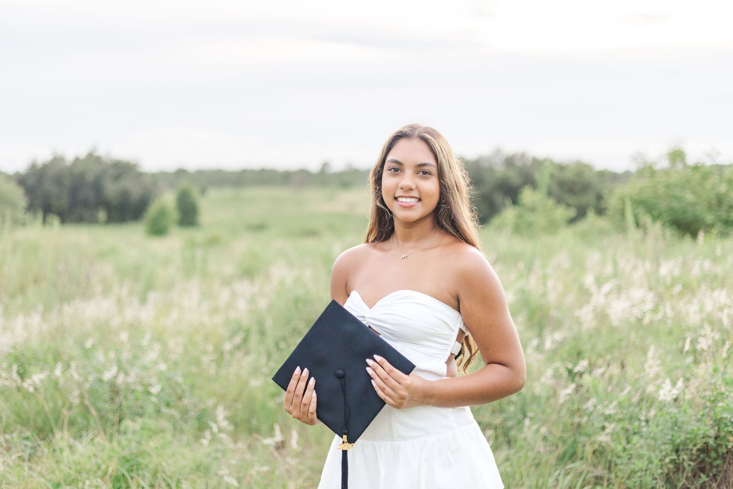 Joyful graduation portraits taken in natural meadow setting.
