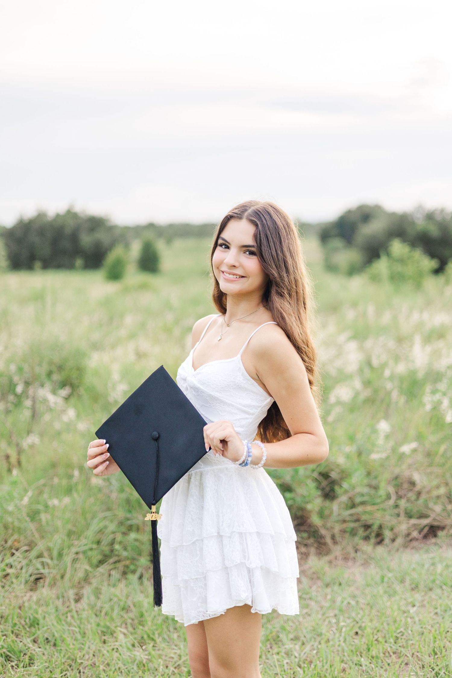 Celebratory graduation photos captured in blooming summer meadow.