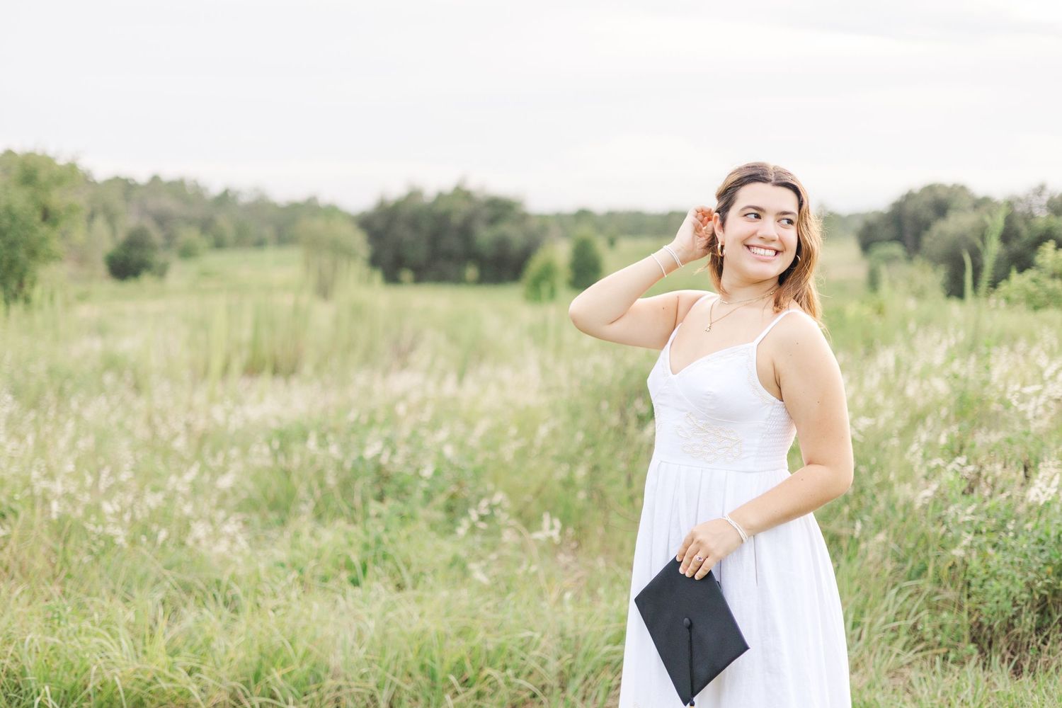 Artistic graduation photography in rustic outdoor setting with wildflowers.