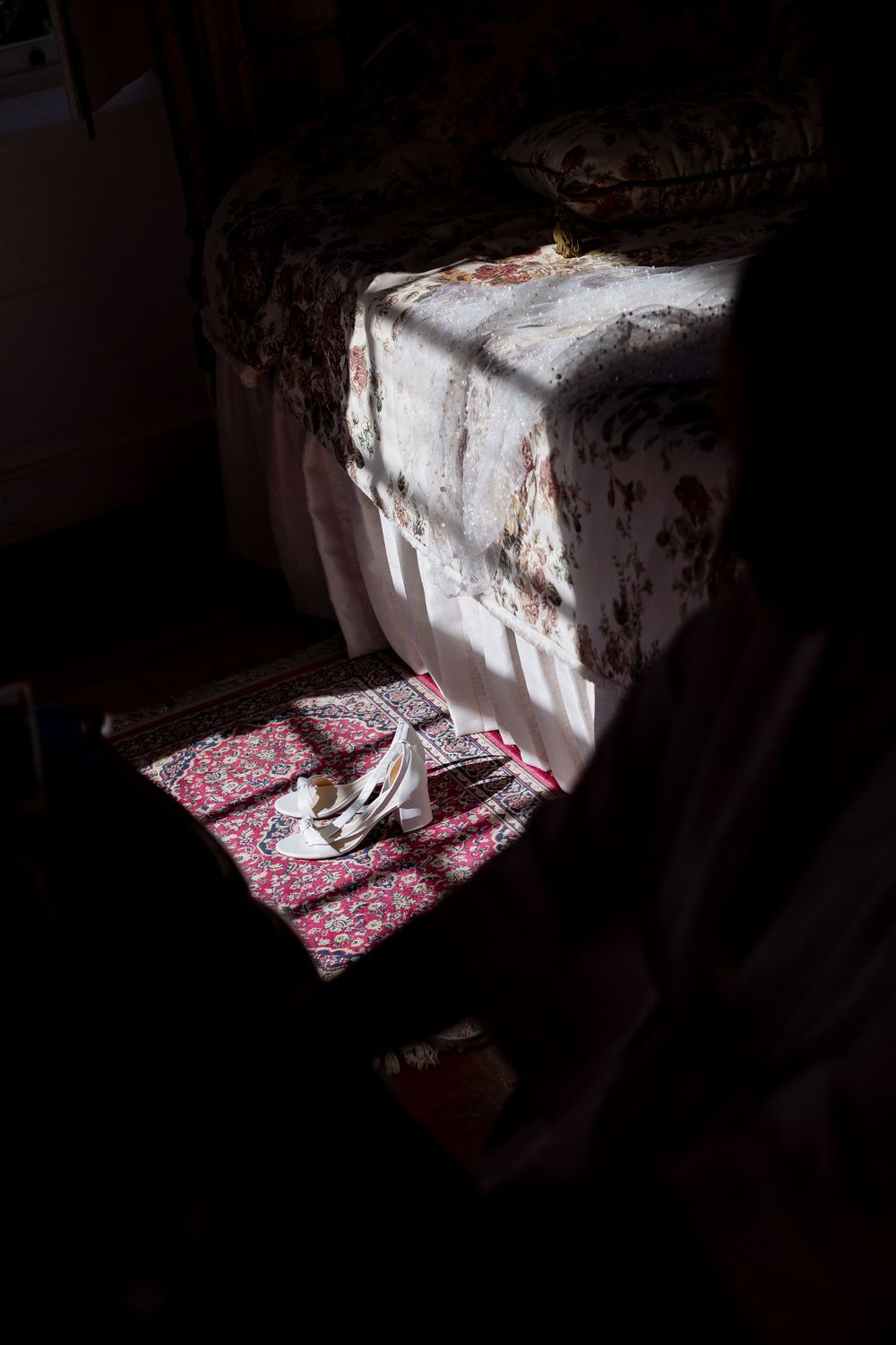 A red patterned textile illuminated by dramatic shadows and light through a window.