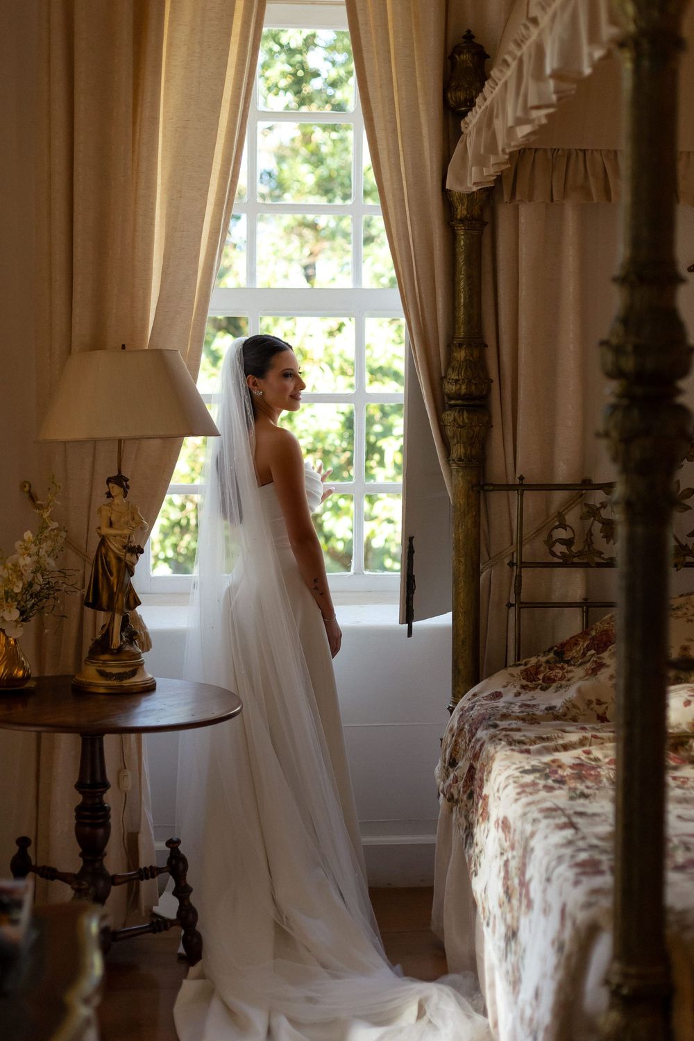 Ethereal white wedding veil cascades through a sunlit room with antique furniture and tall windows.