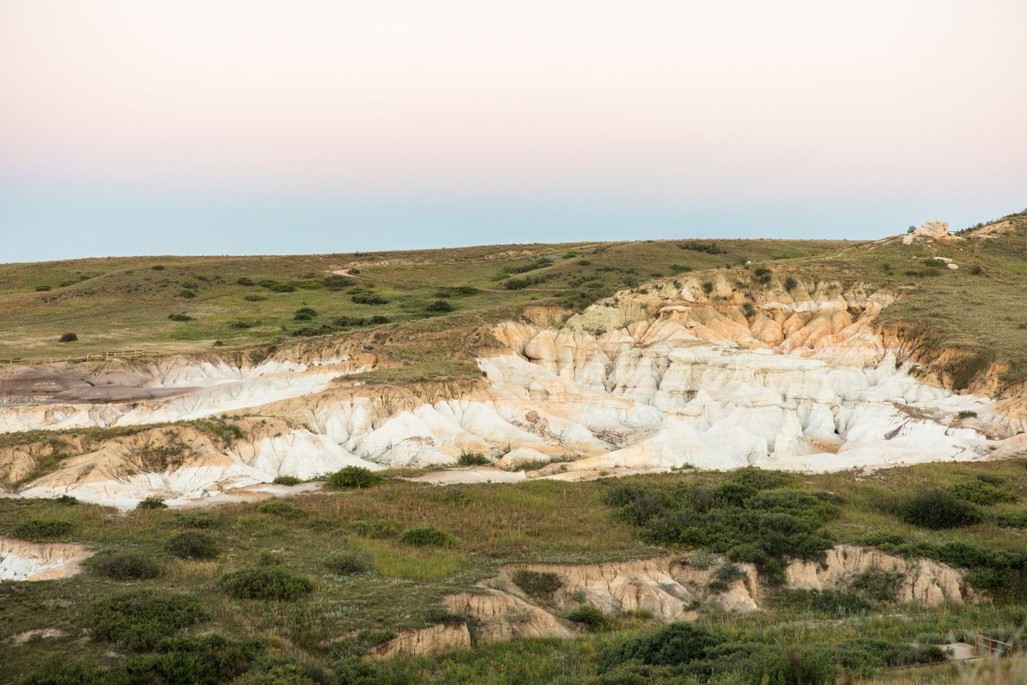 A panoramic view of rugged desert cliffs and layered rock formations stretches across the barren landscape.