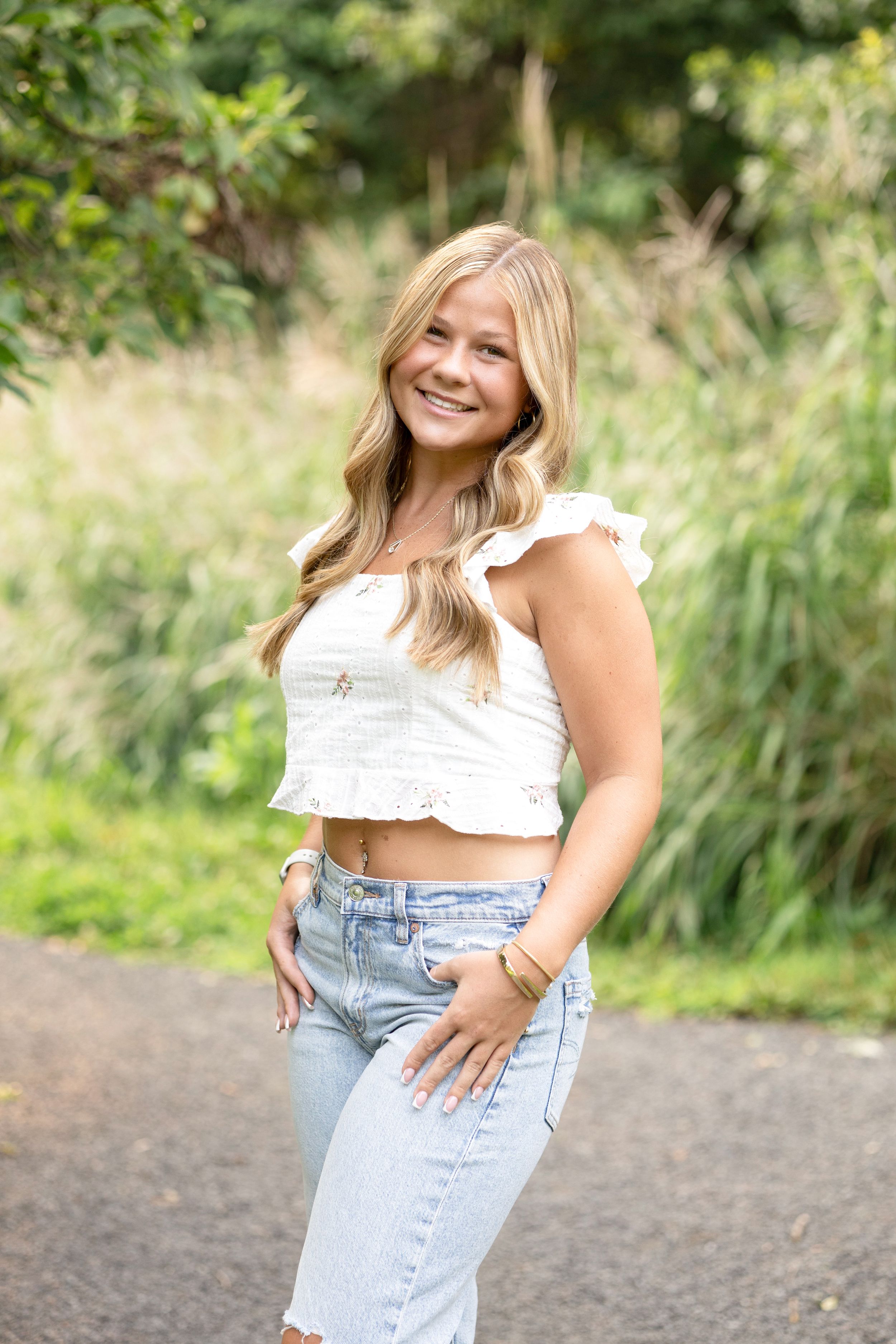 Casual outdoor portraits in white top and light denim against natural backdrop.