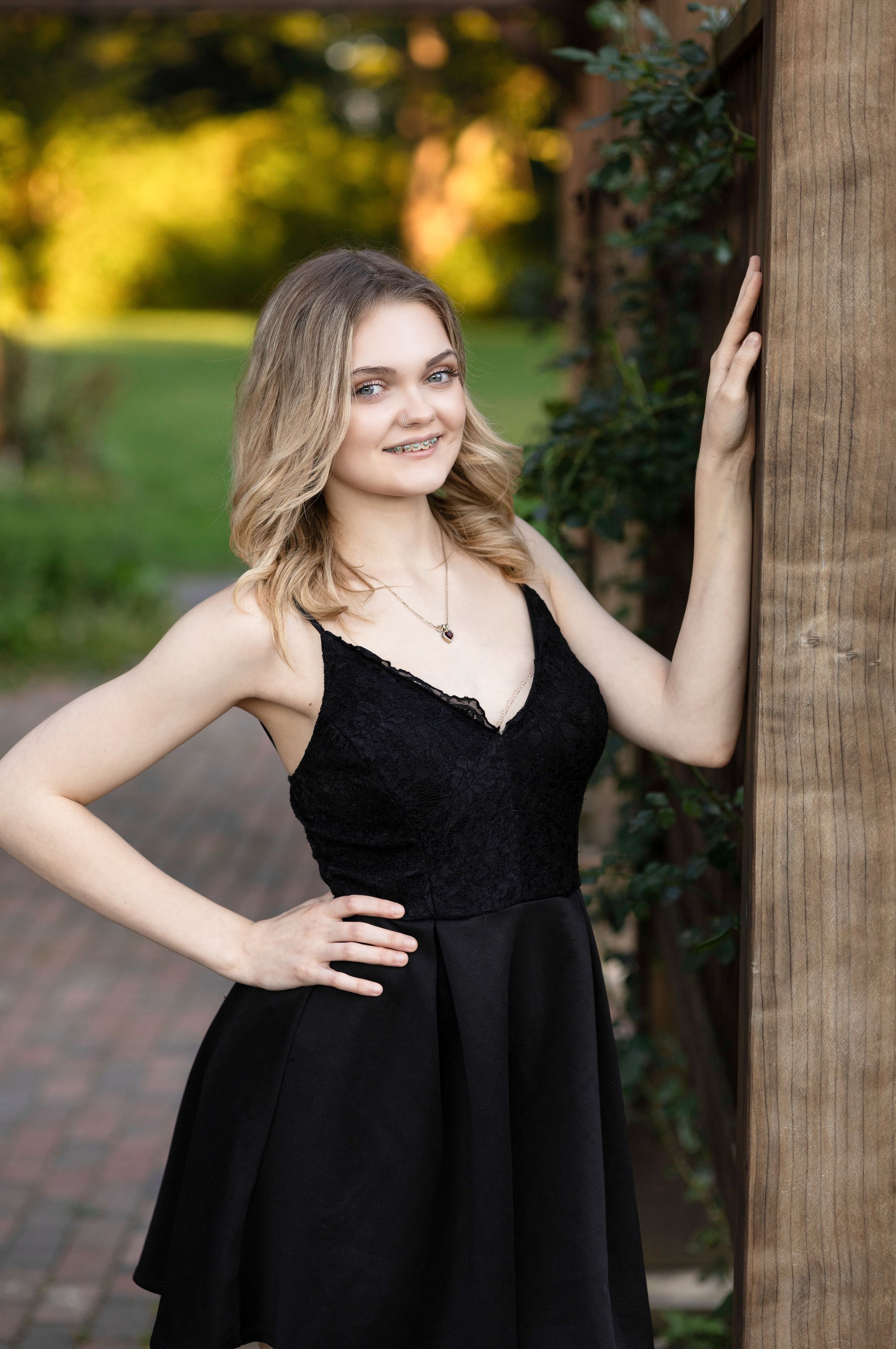 Portrait series against wooden post with black dress and natural lighting.