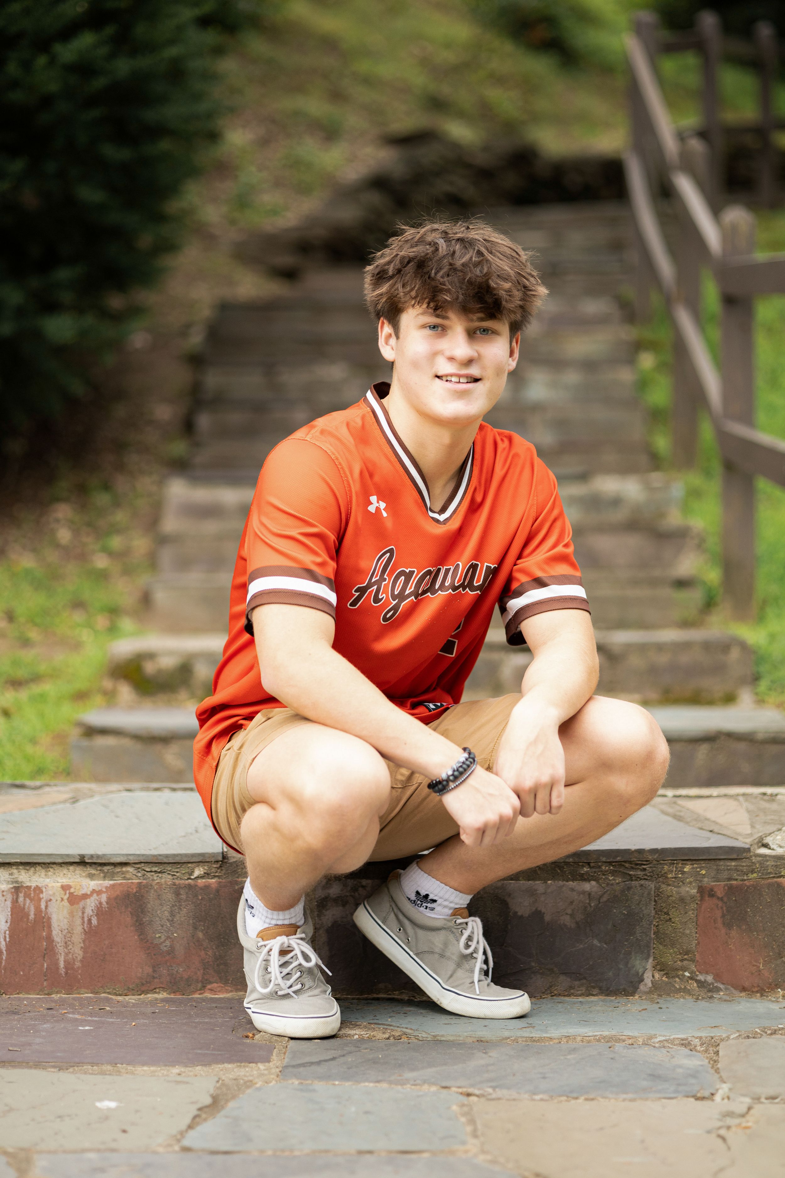 Portrait series on brick steps wearing orange sports jersey.