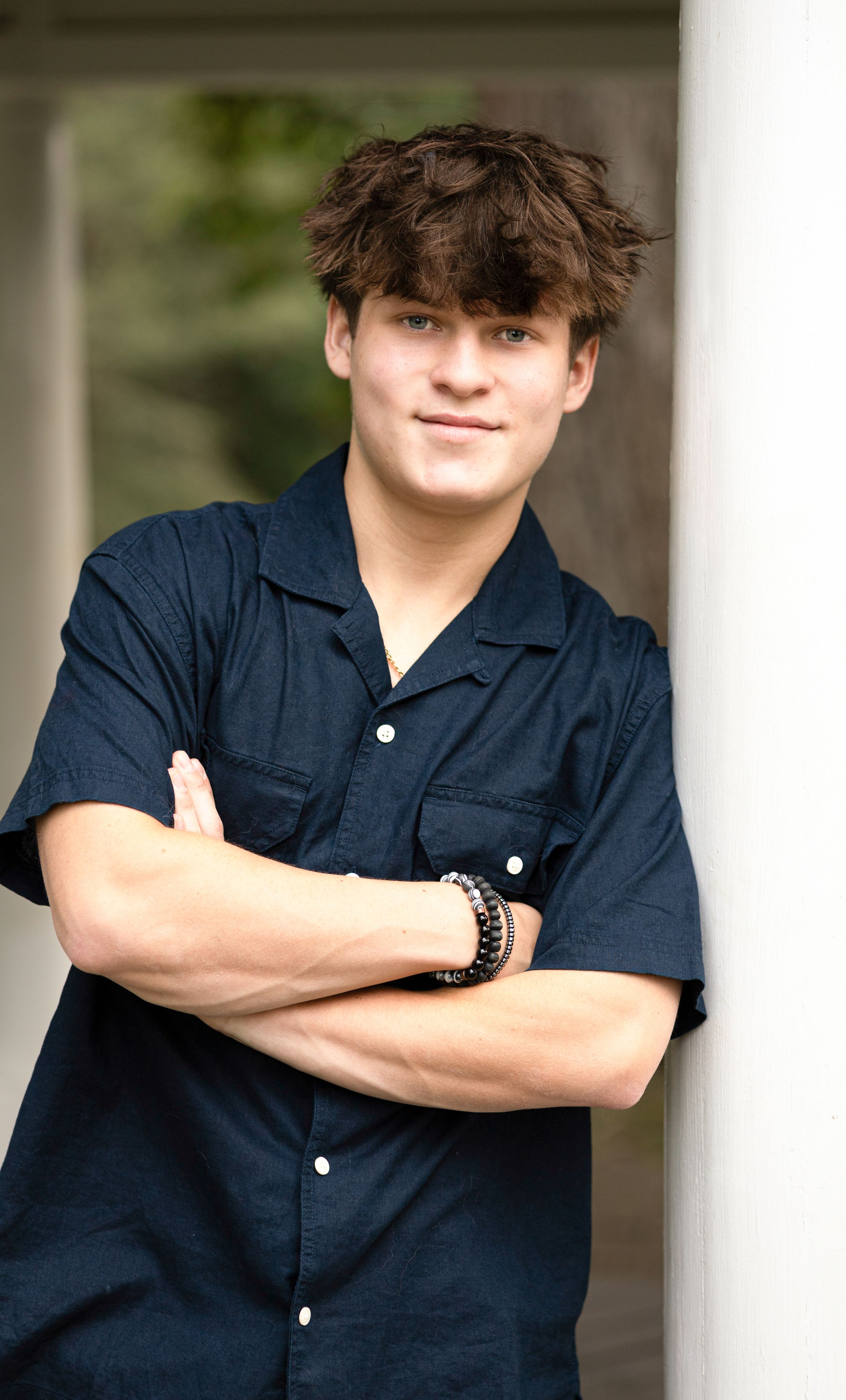 Portrait series in navy button-down shirt against white columns.
