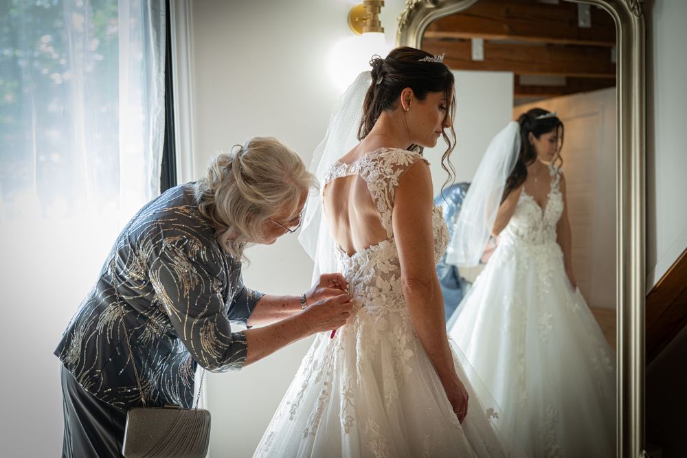 Final wedding dress preparations in sunlit room with intricate lace details.