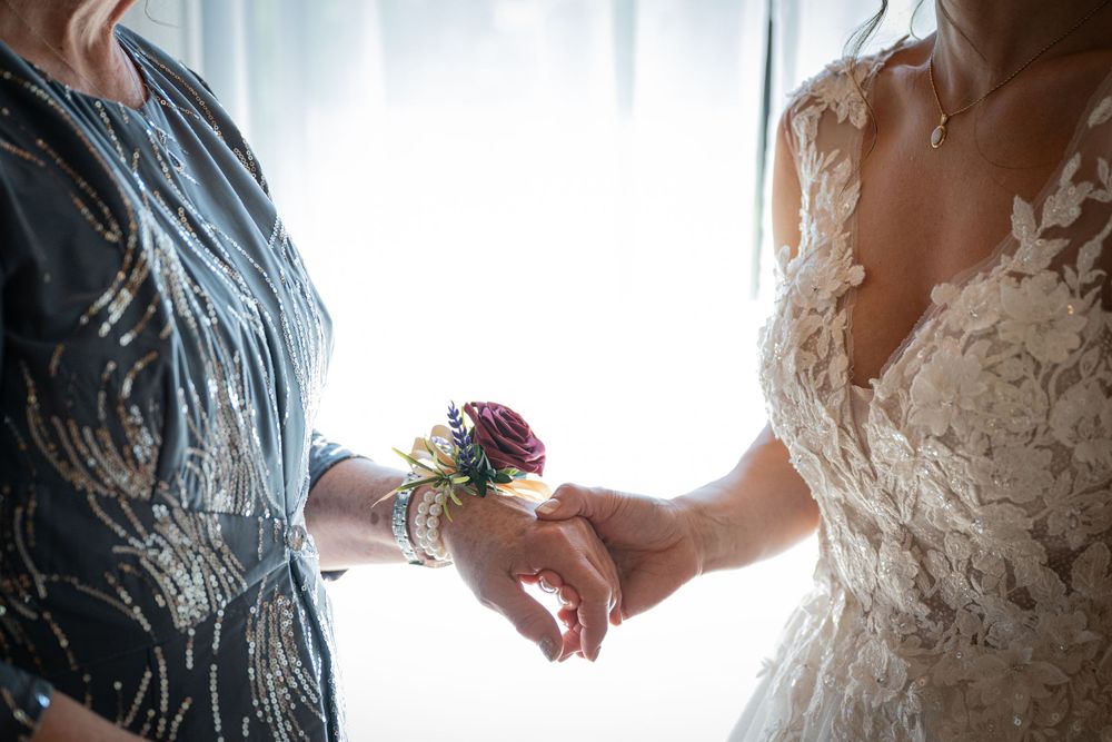 A tender moment as someone pins a corsage on a bride wearing a delicate lace wedding dress.