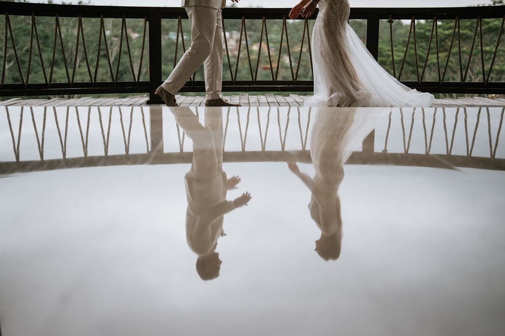 Artistic reflection shot of couple dancing on polished floor at wedding venue.
