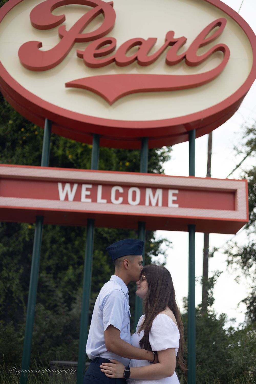 A couple shares an intimate moment in front of a retro-style storefront with a red curved awning.