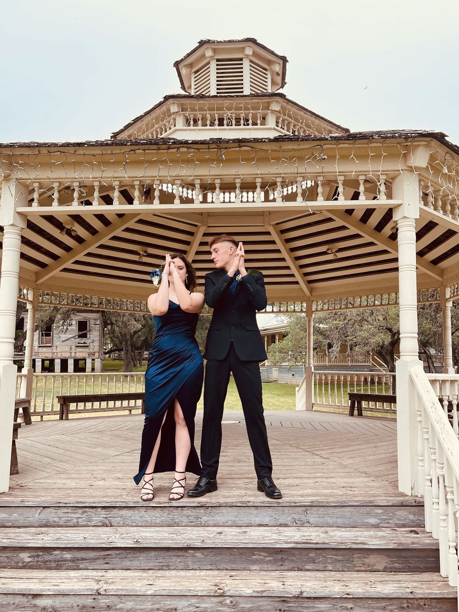 A couple dancing in an ornate white gazebo with Victorian architectural details and decorative trim.