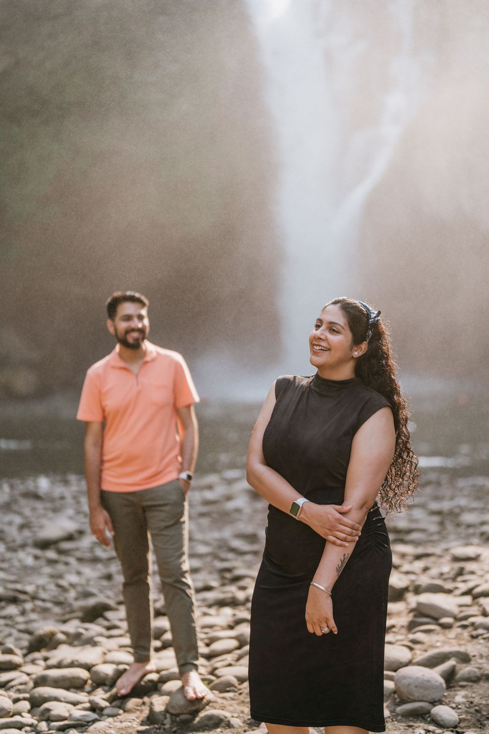 Two people share joyful laughter while standing on rocky terrain with dramatic lighting.