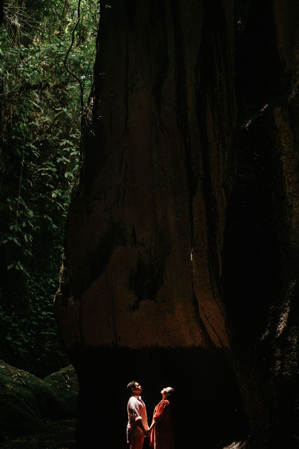 Two figures in light and dark clothing standing in a dramatic forest clearing.