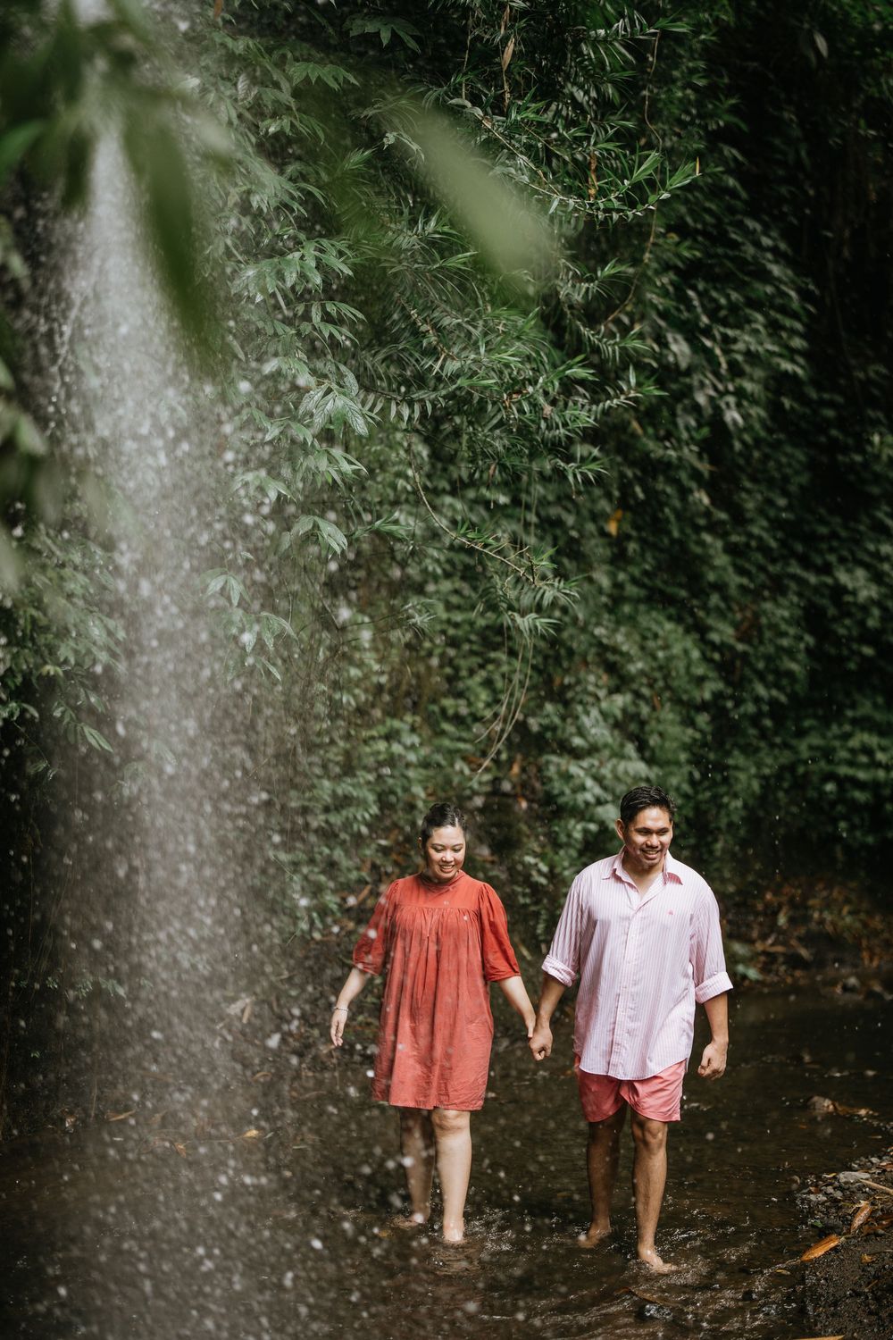 Two people stroll together through dense tropical foliage.