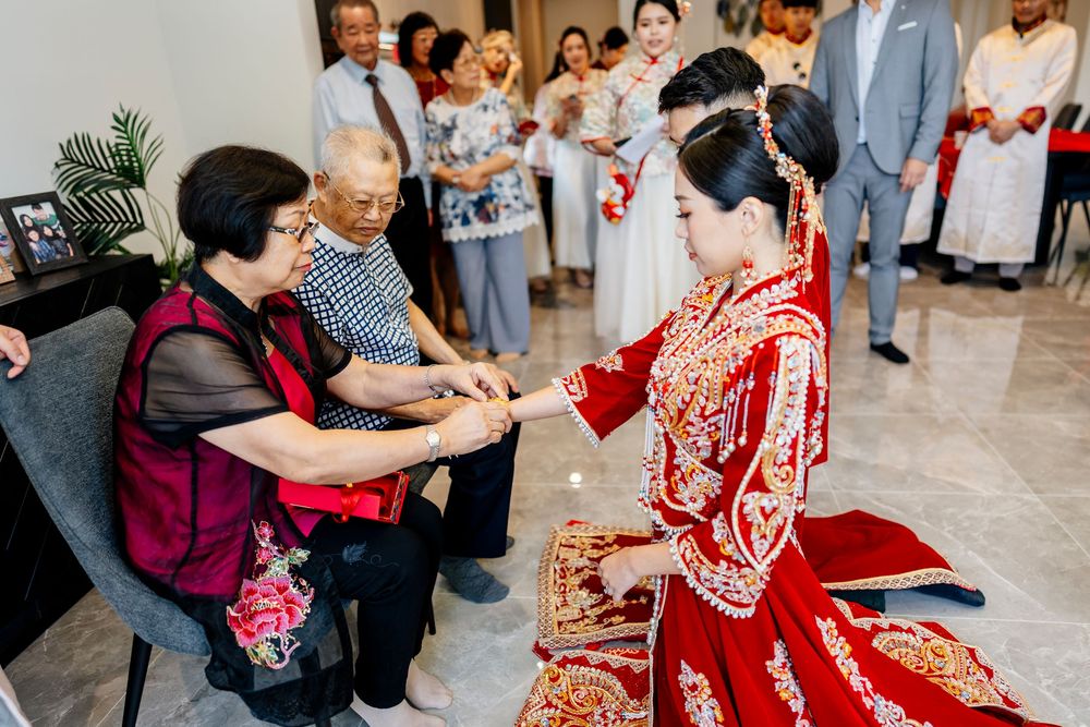 Guests gather around during traditional Chinese tea ceremony in bright indoor setting.