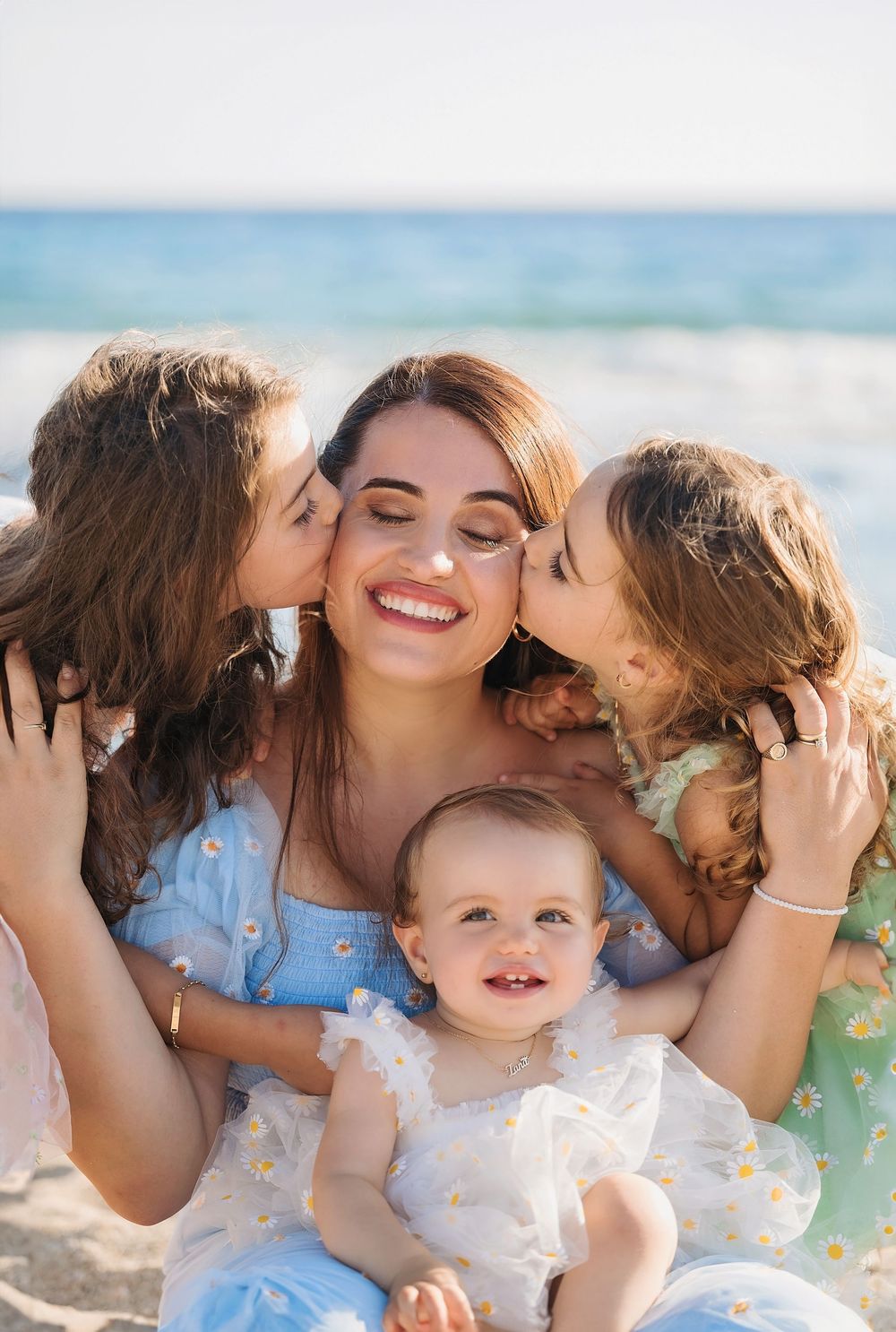 A joyful beach family moment as children give kisses on a sunny day by the ocean.