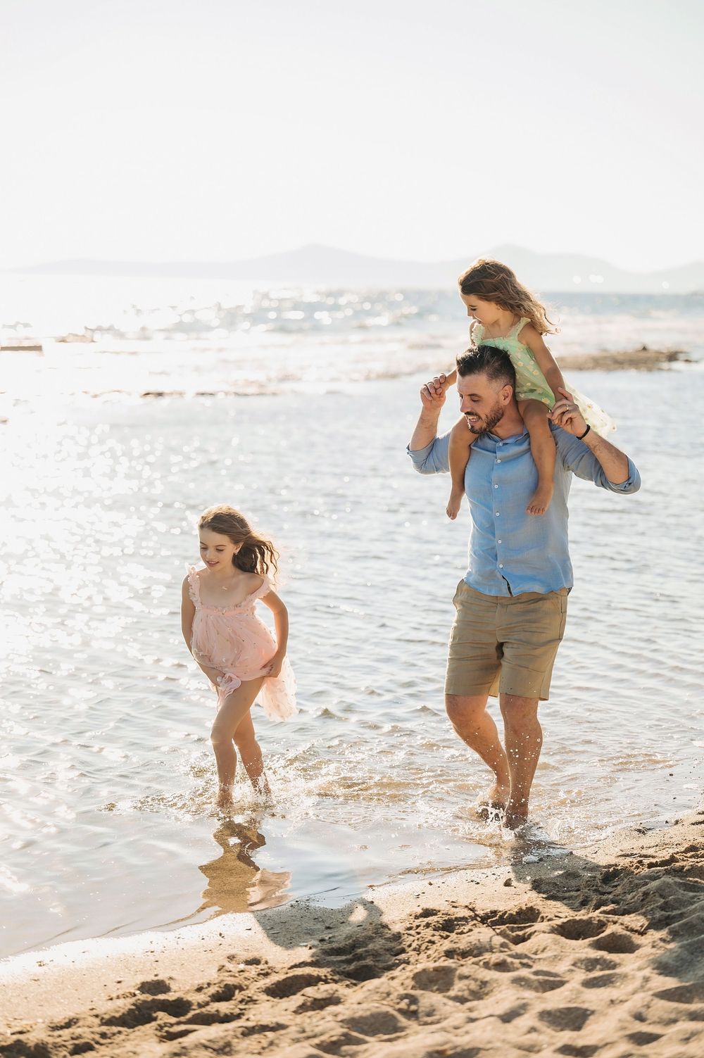 A family wading in the ocean waves together during a beach photo session.