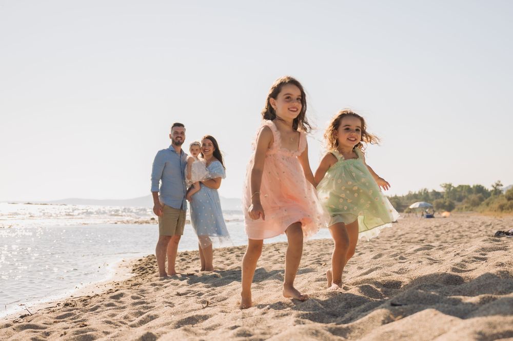 A family enjoys a playful moment together while walking along a beach at sunset.