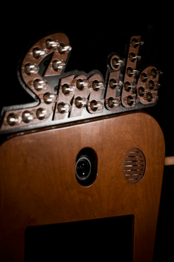 Close-up view of wooden mechanical toy head components with metal screws and gears on dark background.