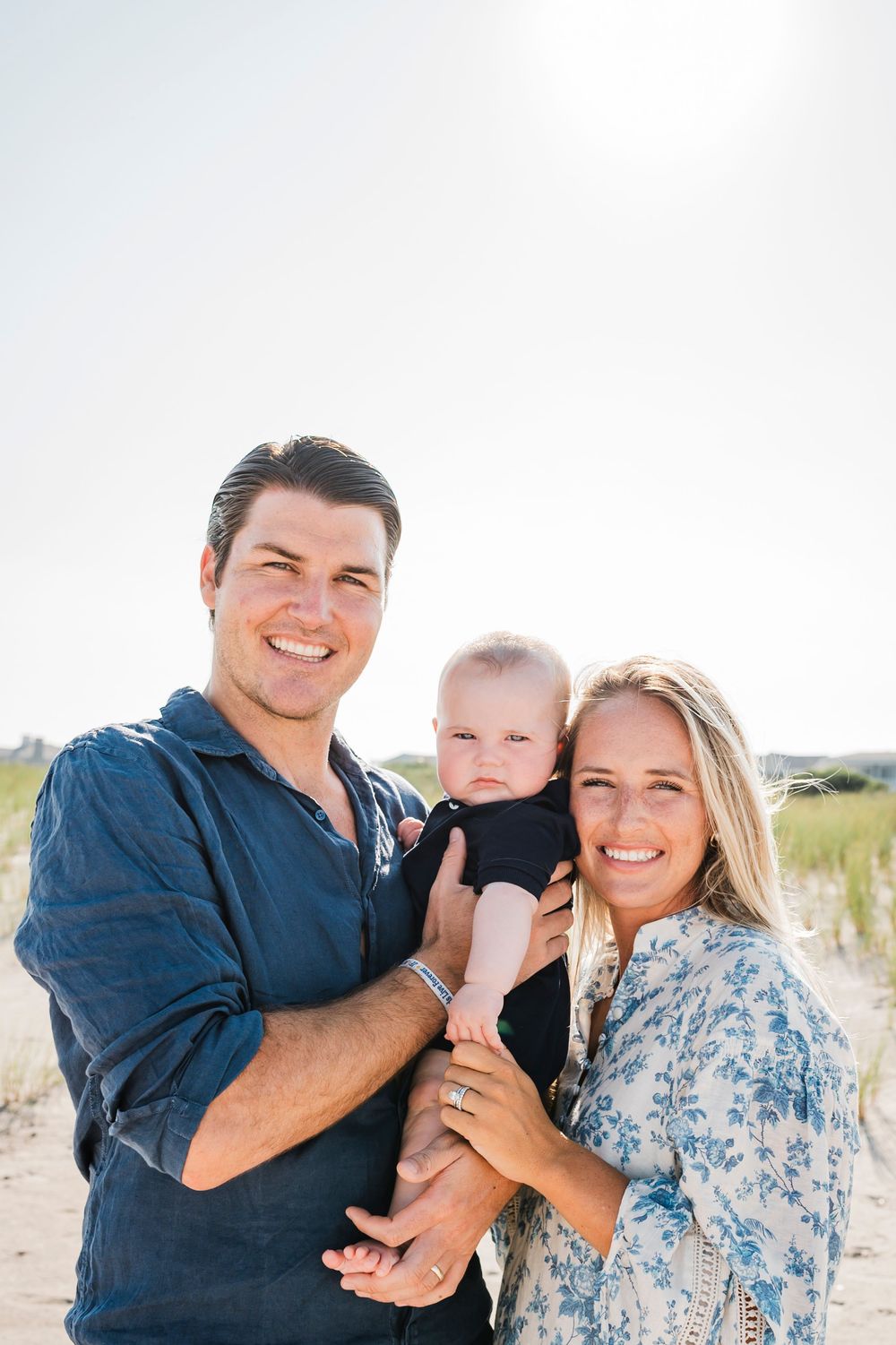 Family portrait on a sunny beach with sand dunes in the background.