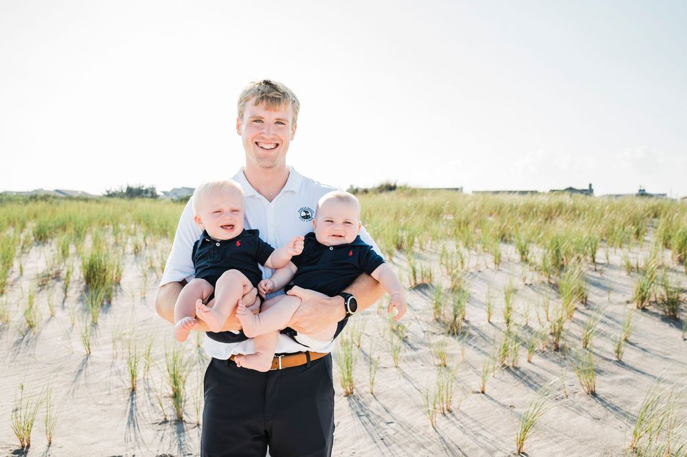 Happy family enjoying quality time together at the beach with sand dunes and grass in the background.
