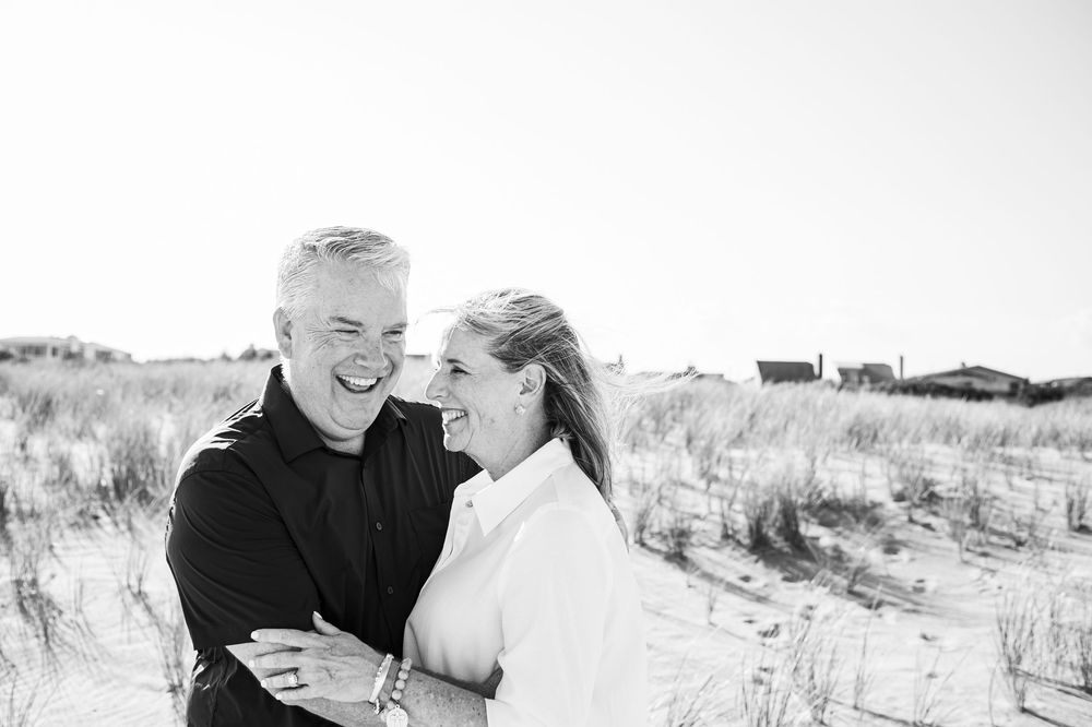 Joyful moment captured at a scenic beach setting with sand dunes and natural coastal vegetation.