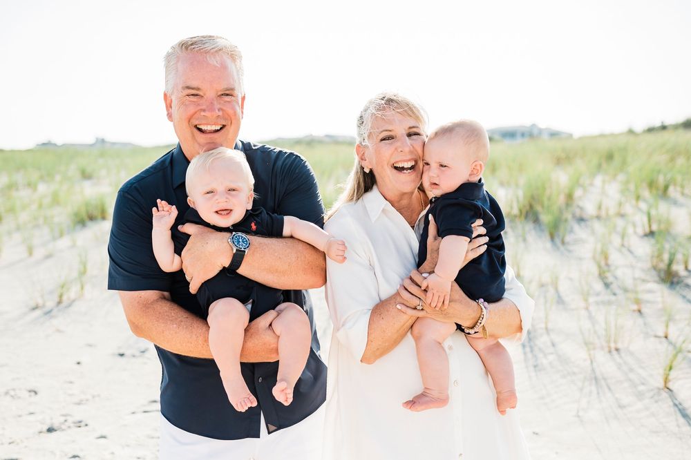 Joyful family moment captured against coastal dunes on a bright day.