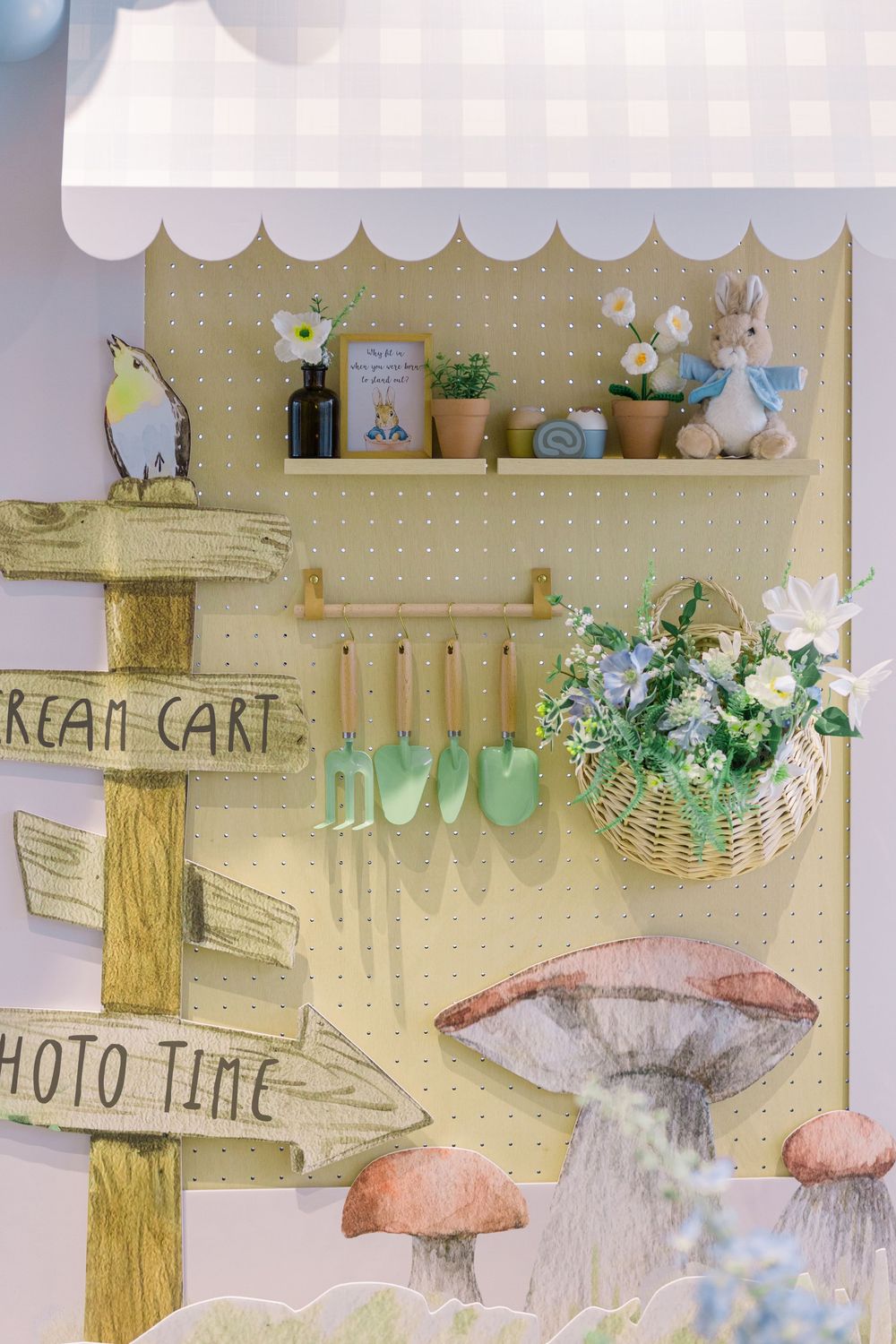 Rustic wooden pegboard wall display with decorative mushroom shapes and hanging baskets in a whimsical garden theme.