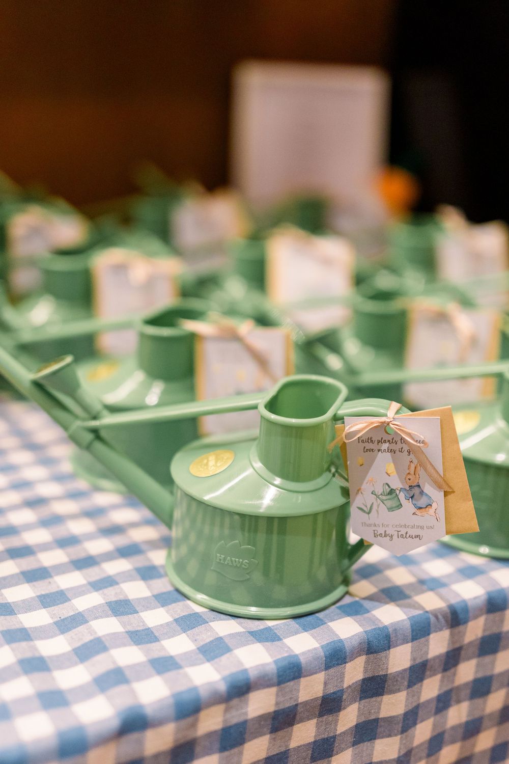 Green teacups with saucers lined up on a blue and white checkered tablecloth create a charming vintage tea party setting.