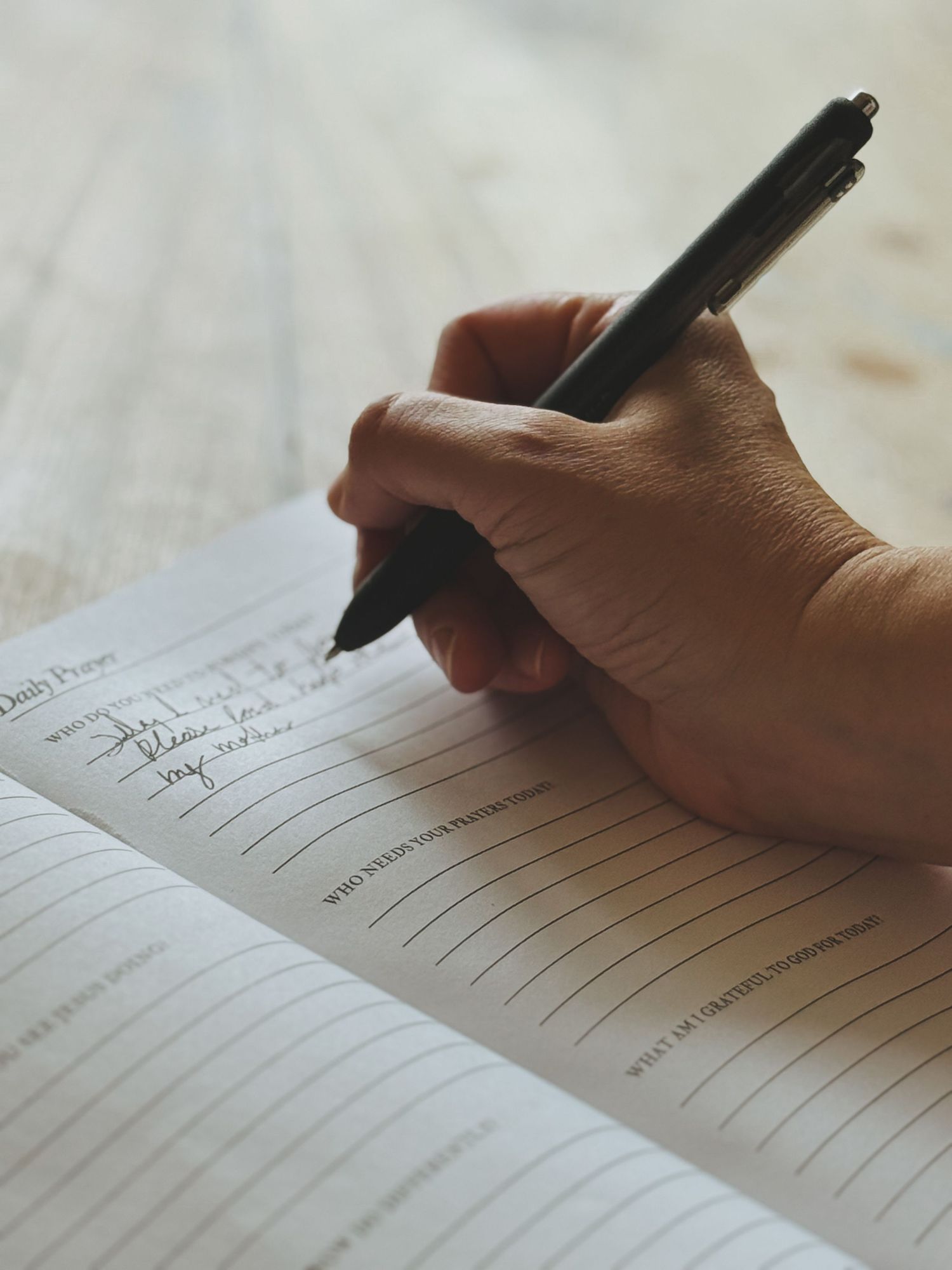 Close-up view of hands writing on lined paper with a black pen showing multiple sequential writing moments.