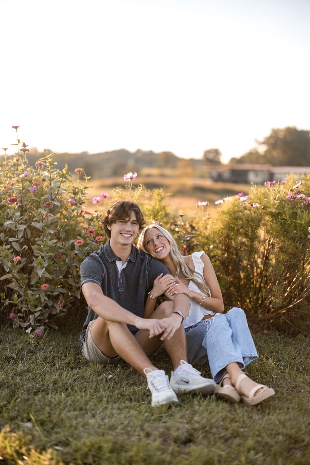Couple relaxing together in a golden field at sunset with wildflowers and natural scenery in the background.
