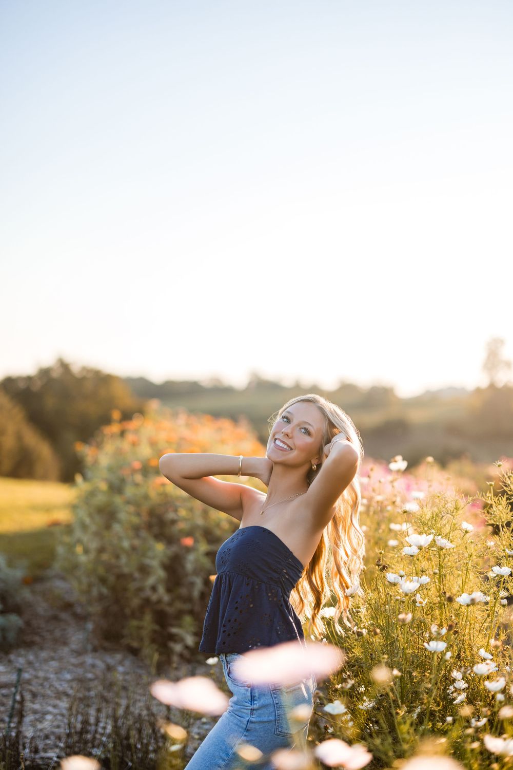 A joyful summer portrait session among blooming white daisies and wildflowers at sunset in a meadow.