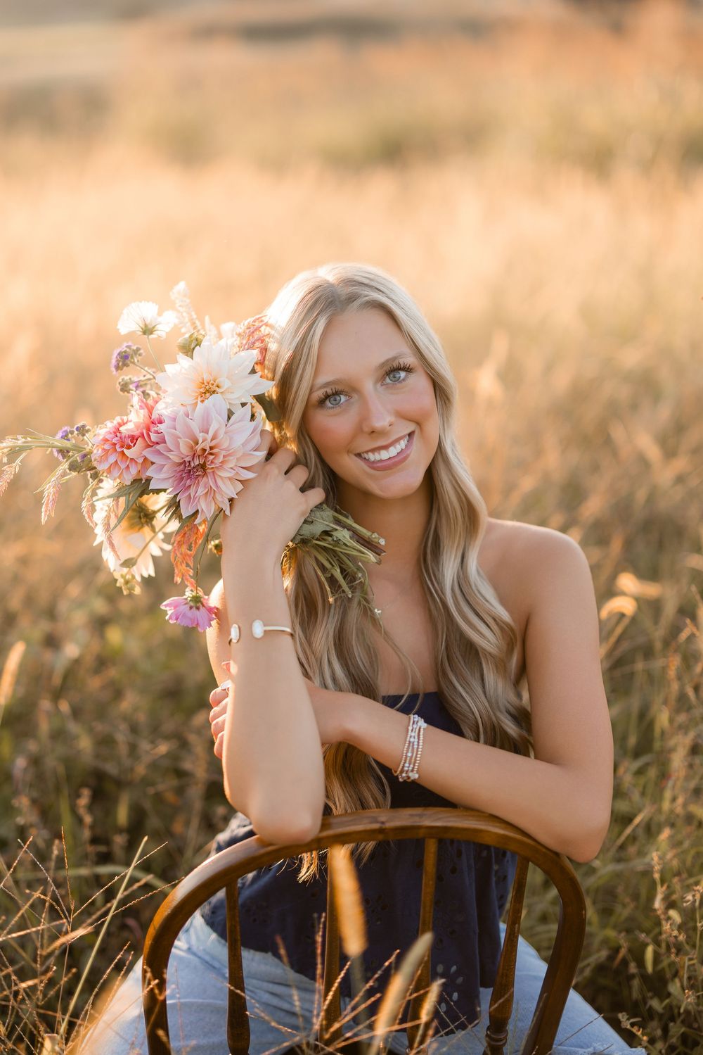 Golden sunlit field with vintage wooden chair and pink gerbera daisy bouquet in warm summer evening light.
