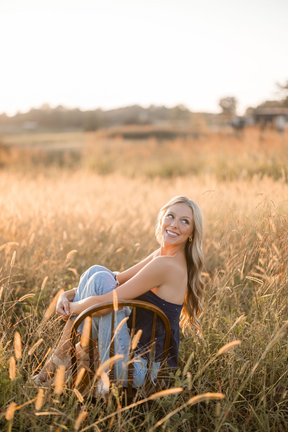 Person relaxing in golden wheat field at sunset with warm glowing light creating dreamy atmosphere.