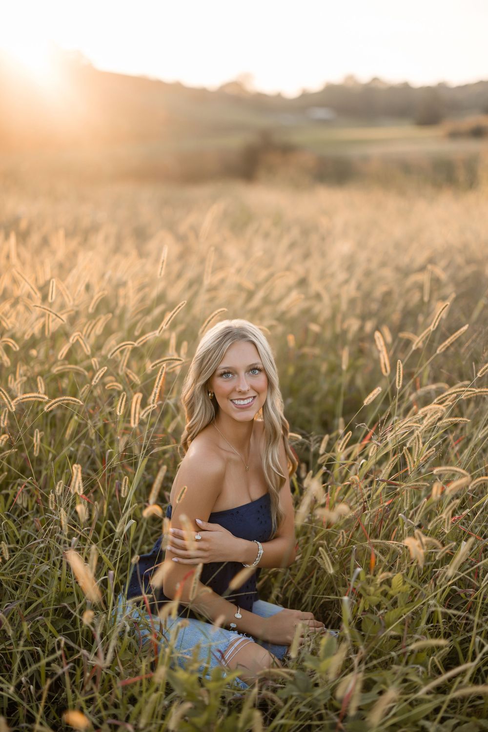 Someone poses playfully in a cornfield during golden hour wearing casual summer attire.