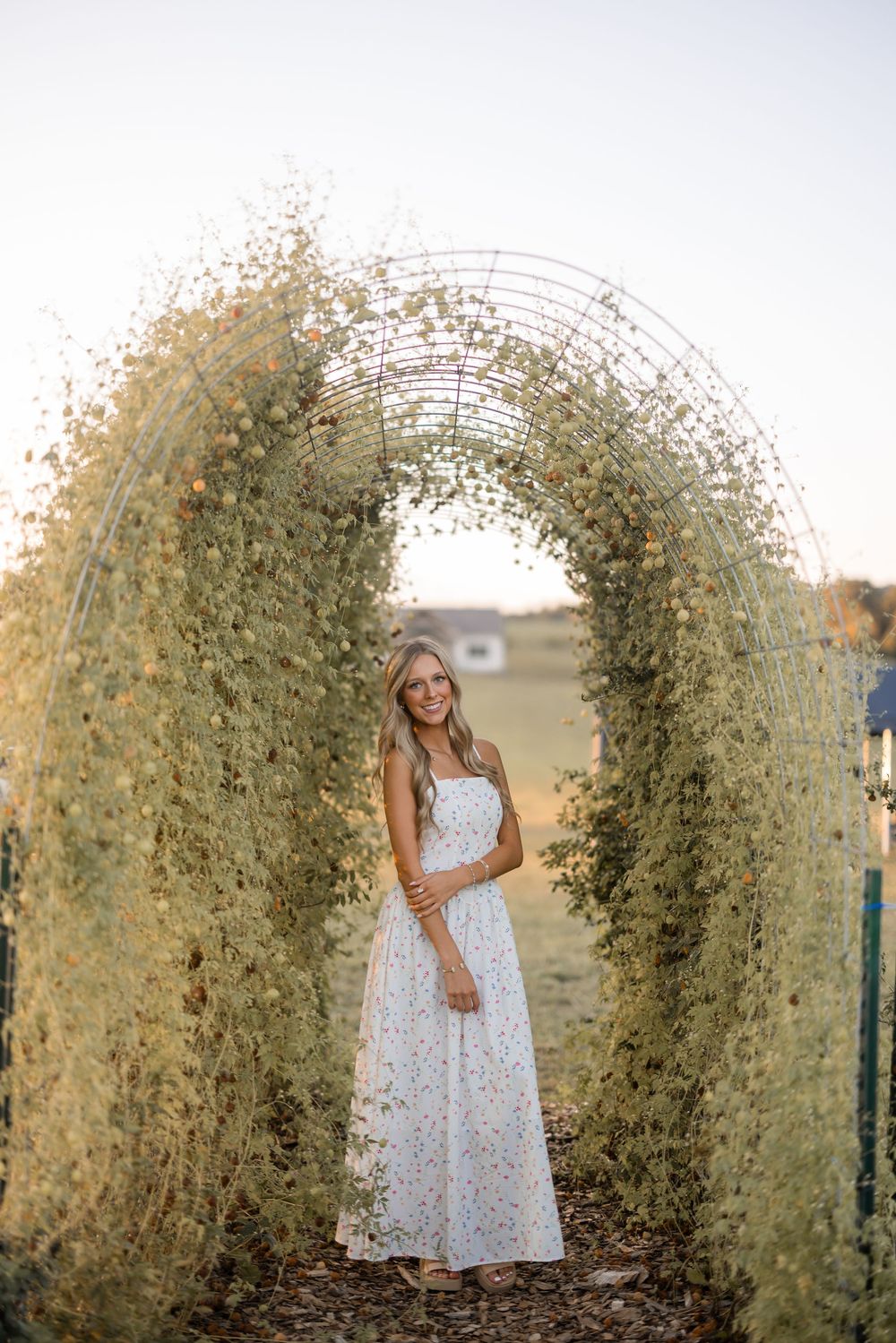 A summer portrait under an arching floral trellis covered in delicate white blooms.