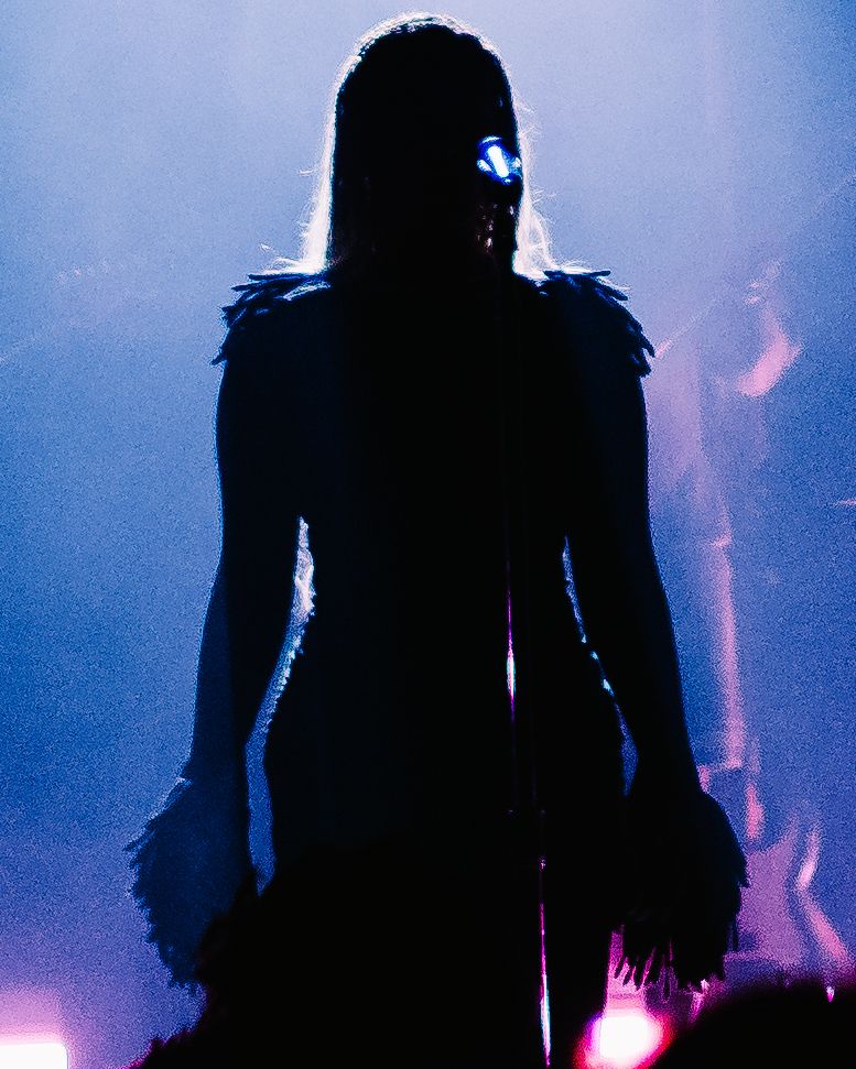 Silhouetted figures stand in a dramatic backlit scene with purple and blue atmospheric lighting effects.