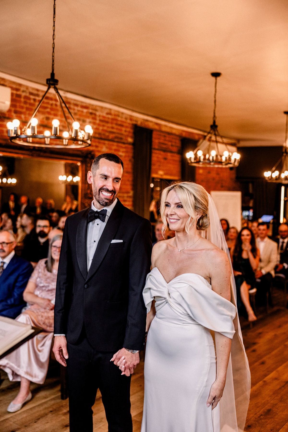 Bride and groom walking hand in hand near lakefront venue in Ontario