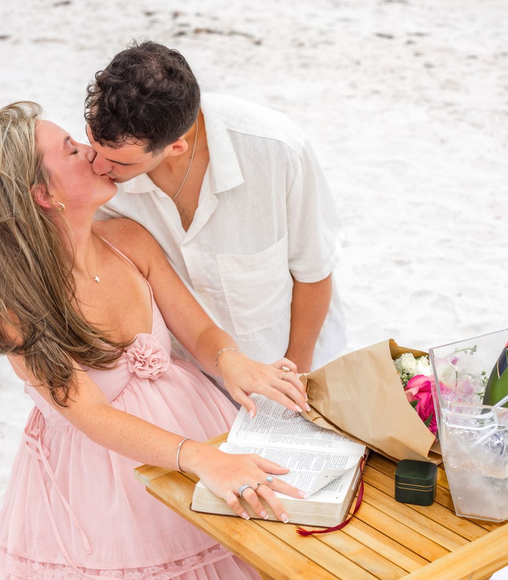 Couple sharing a romantic moment while sitting at a wooden table outdoors.